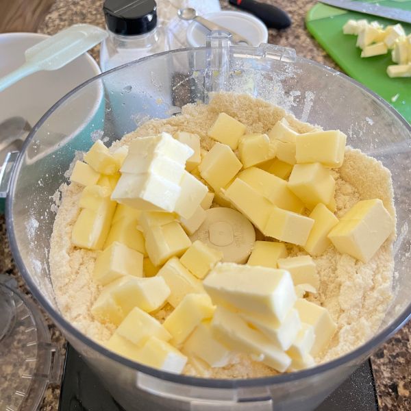 Chilled, cubed butter is scattered on the flour mixture.